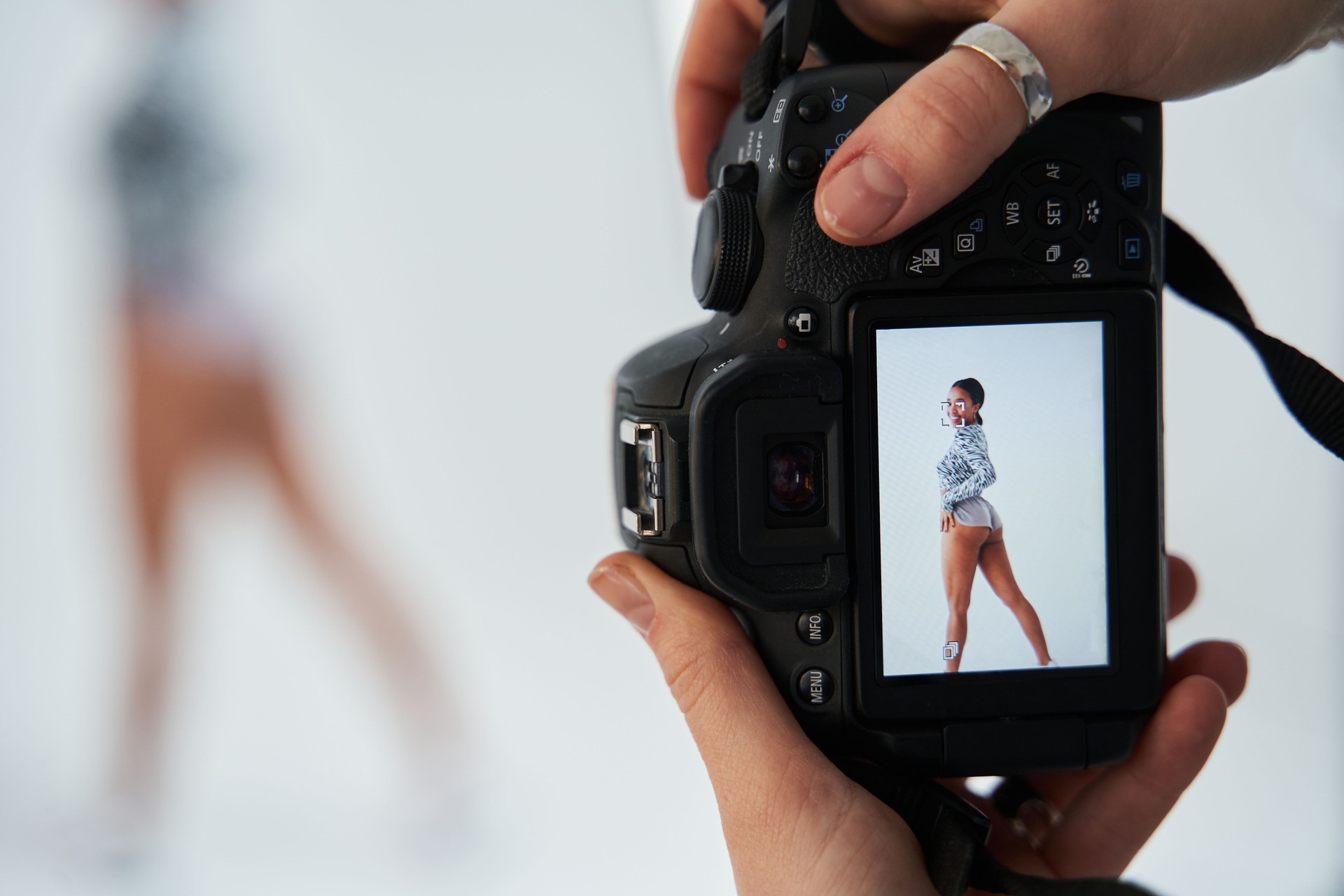Photographer holding camera with multiracial dancer girl at the screen. Backstage concept